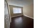 A spacious bedroom with neutral walls and dark wood-look flooring, featuring a large window with blinds at 4701 S Texas Ave # 4701A, Orlando, FL 32839