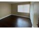 A spacious bedroom with neutral walls and dark wood-look flooring, featuring a large window with blinds at 4701 S Texas Ave # 4701A, Orlando, FL 32839