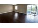 An open living room with wood-look floors, neutral walls, natural light, and a sliding glass door to the outside at 4701 S Texas Ave # 4701A, Orlando, FL 32839
