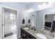 Ensuite bathroom with double vanity, granite countertop, and walk-in shower with clear glass doors at 4733 Cliveden Loop, Sanford, FL 32773