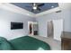 Bright main bedroom with a blue tray ceiling, ceiling fan, TV, mirror, and ensuite bath and walk-in closet at 4733 Cliveden Loop, Sanford, FL 32773