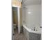 Corner soaking tub with tiled walls and gray plank flooring in this well-lit bathroom at 5821 La Costa Dr # 108, Orlando, FL 32807