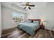 Bedroom with tray ceiling, ceiling fan, wood-look flooring, and large window at 6566 S Goldenrod Rd # 82A, Orlando, FL 32822