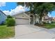 Exterior showcasing a lush lawn, a two-car garage, and an attractive tree providing shade to the property at 6720 Winder Lynne Ln, Orlando, FL 32819
