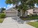 Charming home with a well-maintained lawn, two-car garage, and mature tree shading the facade at 6720 Winder Lynne Ln, Orlando, FL 32819