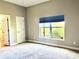 Simple bedroom with a large window with blue blinds and neutral colors at 800 Sterling Chase Dr, Port Orange, FL 32128