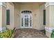Close-up of the front door, highlighted by decorative glass, sidelights, transom window and brick paver patio at 800 Sterling Chase Dr, Port Orange, FL 32128