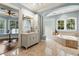 Elegant bathroom with a soaking tub, glass block window, and vanity with decorative lighting at 8542 Eden Park Rd, Orlando, FL 32810
