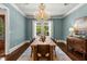 Light blue dining room featuring a large chandelier and table, complemented by hardwood floors at 8542 Eden Park Rd, Orlando, FL 32810