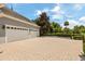 View of the three car garage with a paved driveway and lovely landscaping at 8542 Eden Park Rd, Orlando, FL 32810