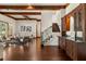 Open-concept living room with wood beam ceilings, hardwood floors, wet bar, and a staircase with decorative ironwork at 8542 Eden Park Rd, Orlando, FL 32810