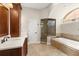 Bathroom featuring dark wood cabinets, soaking tub, and glass-enclosed shower at 8800 Torey Pines Ter, Orlando, FL 32819