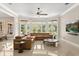 Spacious living room with a leather sectional sofa, large windows, and a ceiling fan at 8800 Torey Pines Ter, Orlando, FL 32819
