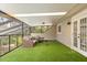 The bright sunroom features artificial turf, a full screen enclosure and comfortable seating for enjoying the outdoors, inside at 8800 Torey Pines Ter, Orlando, FL 32819