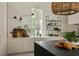 Bright kitchen with stone countertops, white cabinets, shelving, and a window view of greenery at 1150 Via Salerno, Winter Park, FL 32789