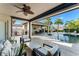 Covered outdoor area with a ceiling fan and comfortable seating overlooking the pool, summer kitchen, and dining space at 11754 Waterstone Loop Dr, Windermere, FL 34786