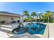 Sparkling swimming pool surrounded by travertine tile, lush palm trees, and an outdoor dining area with a summer kitchen at 11754 Waterstone Loop Dr, Windermere, FL 34786