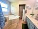 A well-lit bathroom featuring a soaking tub with tile surround and vanity with sink at 1212 Bradwell Dr, Orlando, FL 32837