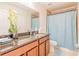 Bathroom featuring granite countertop, tiled shower with blue curtain, and wood cabinetry at 1639 Balsam Willow Trl, Orlando, FL 32825