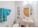 Bathroom with pedestal sink, round mirror, and decorative towels and artwork at 1639 Balsam Willow Trl, Orlando, FL 32825