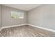 A quaint, empty bedroom includes plank flooring, neutral colored walls, and a window with blinds at 2078 Keyes Ln, Deltona, FL 32738