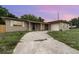 Single story home with brick detail, stucco exterior, and long driveway under a colorful sky at 2078 Keyes Ln, Deltona, FL 32738