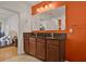Bathroom featuring double sinks with black countertops, orange accent wall, and adjoining bedroom at 2216 Sequoia Way, Davenport, FL 33896