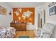 A cozy bedroom with an orange accent wall, hardwood floors and a sitting area at 2216 Sequoia Way, Davenport, FL 33896