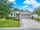 Well-maintained single-Gathering home with a two-car garage, green lawn and mature landscaping at 2216 Sequoia Way, Davenport, FL 33896