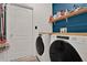 Laundry room with white washer and dryer set, tile floors, and a dark blue accent wall at 2216 Sequoia Way, Davenport, FL 33896