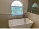 Freestanding soaking tub with modern fixtures and a window at 2299 Rock Dr, Poinciana, FL 34759