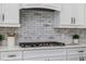 Gas cooktop range set in quartz countertop with marble backsplash and white cabinetry at 2354 Emerald Springs Dr, Apopka, FL 32712