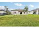 A spacious backyard with lush green grass and a well-maintained beige exterior, featuring sliding glass doors at 3093 Neverland Dr, New Smyrna Beach, FL 32168