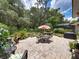 Landscaped backyard featuring a brick patio, barbecue grill, lush greenery, and mature shade trees at 3556 Sunset Isles Blvd., Kissimmee, FL 34746