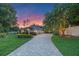 Charming single-story home with brick driveway, manicured lawn, and beautiful landscaping at sunset at 5102 Round Tree Ct, Orlando, FL 32819