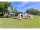 Charming home featuring a backyard deck, light blue doors, and a lush green lawn at 608 Cedar Ave, Holly Hill, FL 32117