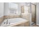 An inviting bathroom with a soaking tub and a glass enclosed shower next to a large window for natural light at 6449 Sprucepine Ln, St Cloud, FL 34771