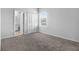 A carpeted bedroom with a window, closet with white doors, and a door leading to an attached bathroom at 6449 Sprucepine Ln, St Cloud, FL 34771