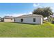 Backyard showing a view of the home's exterior with a sliding glass door and manicured green lawn at 702 Pasteur Ln, Kissimmee, FL 34759