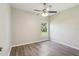 Bright bedroom with wood-look floors, ceiling fan, and window overlooking the green landscape at 702 Pasteur Ln, Kissimmee, FL 34759