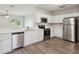Bright kitchen features stainless appliances, white cabinetry, and wood-look flooring, seamlessly flowing to living space at 702 Pasteur Ln, Kissimmee, FL 34759