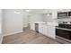 View of the kitchen featuring stainless appliances, white cabinetry, sink and wood-look flooring at 702 Pasteur Ln, Kissimmee, FL 34759