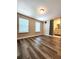 Spacious bedroom featuring wood-look flooring, two windows for natural light, and an adjacent bathroom at 813 Marsh Reed Dr, Winter Garden, FL 34787