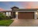 Charming single Gathering home boasting manicured lawn, stone accents, and warm-toned two car garage at 911 Tidal Pond Dr, Groveland, FL 34736