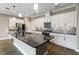 Open kitchen featuring white cabinets, a large island with a sink, and stainless steel appliances at 911 Tidal Pond Dr, Groveland, FL 34736