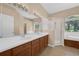 Bright bathroom featuring a double vanity, glass shower, and soaking tub by a sunlit window at 9650 Bay Pine Ln, Orlando, FL 32832