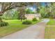 Tan home with a two-car garage and a long driveway surrounded by green landscape and trees at 1102 Winter Springs Blvd, Winter Springs, FL 32708