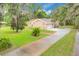 Charming tan home with a long driveway and a two-car garage surrounded by green landscape at 1102 Winter Springs Blvd, Winter Springs, FL 32708