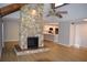 Open-concept living room with a stone fireplace, hardwood floors, and a view of the kitchen at 1102 Winter Springs Blvd, Winter Springs, FL 32708
