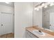 Bright bathroom featuring a vanity with peach countertops, a large mirror, and classic white door at 12843 Madison Pointe # 208, Orlando, FL 32821